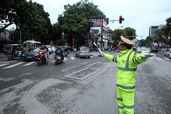 Một chiến sĩ cảnh sát giao thông mặc áo đặc chủng điều khiến giao thông. Đường phố vắng người qua lại