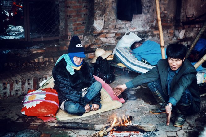 Những người vô gia cư sống dưới chân cầu đang sưởi ấm bằng củi vụn.