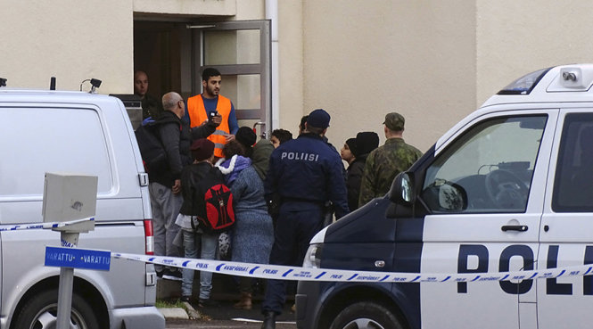 Người nhập cư đi vào trung tâm đăng ký dưới sự giám sát của cảnh sát tại Tornio, Phần Lan - Ảnh: Reuters