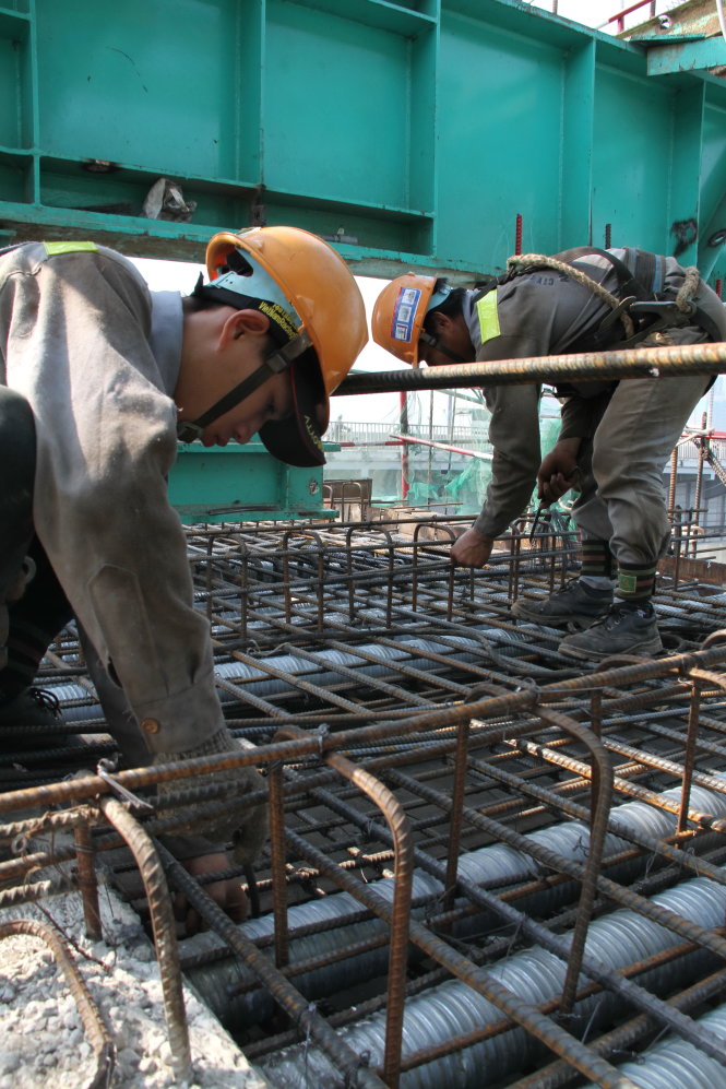 Anh Chí Thanh (quê An Giang) buộc kẽm vào lưới thép để chuẩn bị đổ bêtông sàn dầm cầu metro sáng 1-2 - Ảnh: Phước Tuần