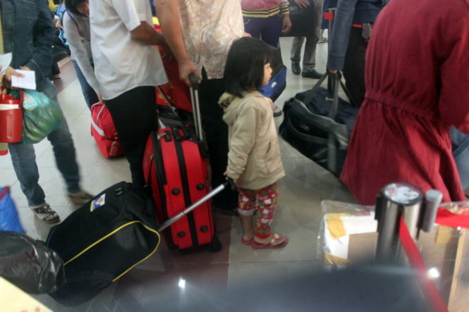 Một em bé kéo hành lý giúp mẹ đi qua cổng kiểm soát vé - Ảnh: Đức Phú