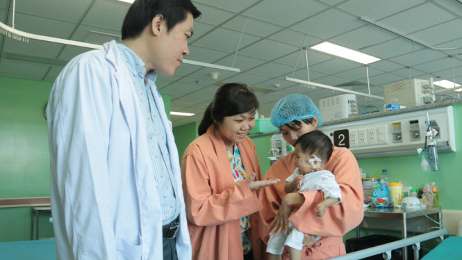 Đại diện báo Tuổi Trẻ trao quà cho chị Nguyễn Thị An (quê Nghệ An) đang chăm sóc cho con gái điều trị tại Khoa hồi sức tim - Ảnh: Tiến Long