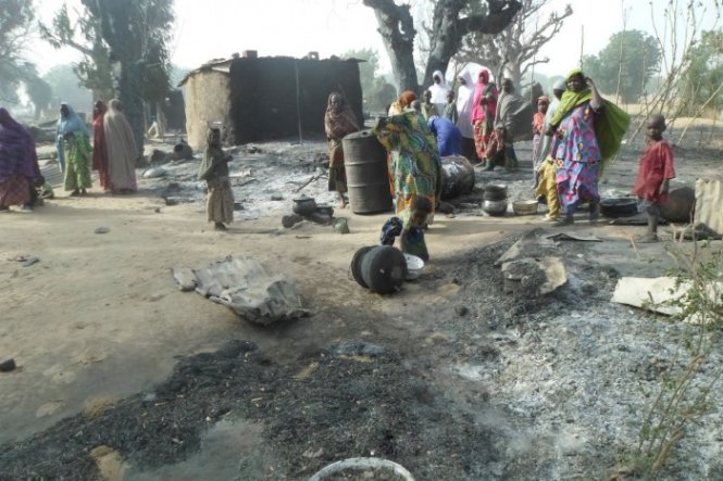 Những người phụ nữ và trẻ em đang đứng nhìn các ngôi nhà cháy tan hoang sau vụ tấn công của lực lượng Boko Haram tại ngôi làng Dalori cách Maiduguri khoảng 5 km ngày 31-1-2016 - Ảnh: AP