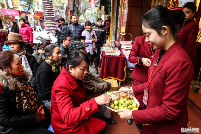 Một nhân viên mang hoa quả để mời những người đang chờ đợi đến lượt vào mua vàng