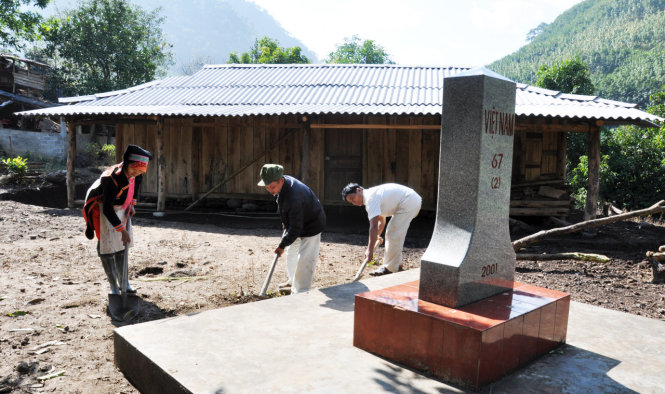 Người dân chăm sóc cột mốc 67 (2) nằm trên sân nhà của dân bản Hùng Pèng (xã Ma Ly Pho, huyện Phong Thổ, Lai Châu) - Ảnh: Việt Dũng