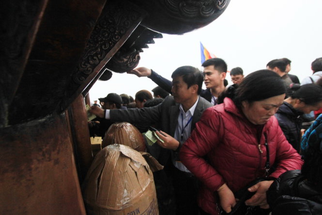 Bất chấp tiếng loa nhắc nhở, hàng trăm người vẫn mải miết dùng tiền “đánh bóng” chùa Đồng trong ngày khai hội Yên Tử - Ảnh: Tiến Thắng