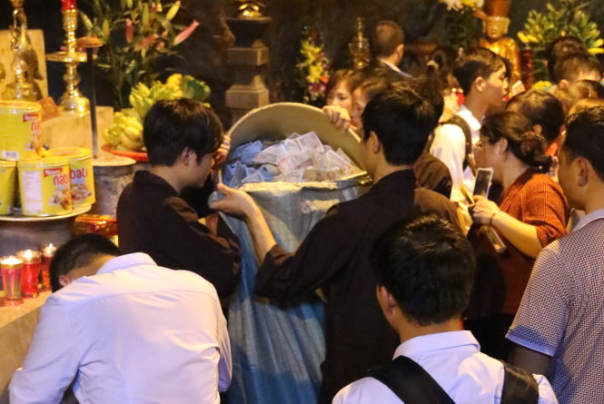 Gom tiền công đức vào bao tải tại lễ hội chùa Hương - Ảnh: T.L.