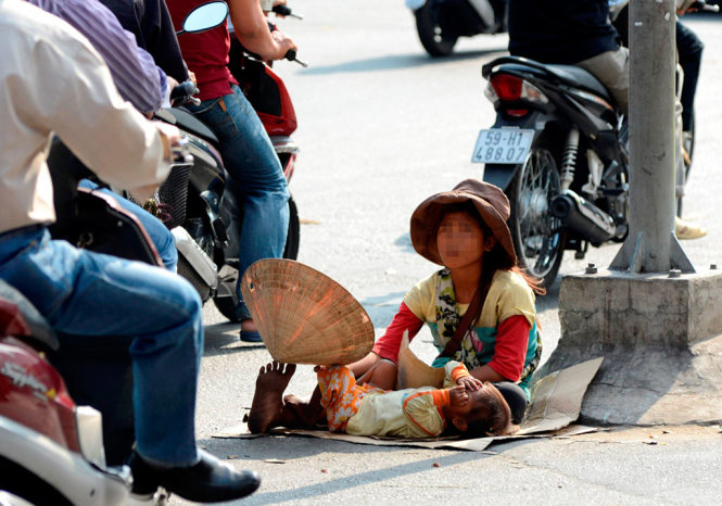 Hai đứa trẻ ăn xin tại góc đường Lý Thường Kiệt - 3 tháng 2 (Q.10, TP.HCM) được một phụ nữ chăn dắt (ảnh chụp chiều 18-2) - Ảnh: Duyên Phan
