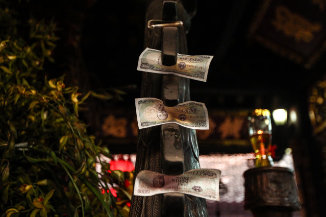 Tiền lẻ được nhét lên mình Hạc đồng được đặt trong đền Thiên Trường - Ảnh: Nguyễn Khánh