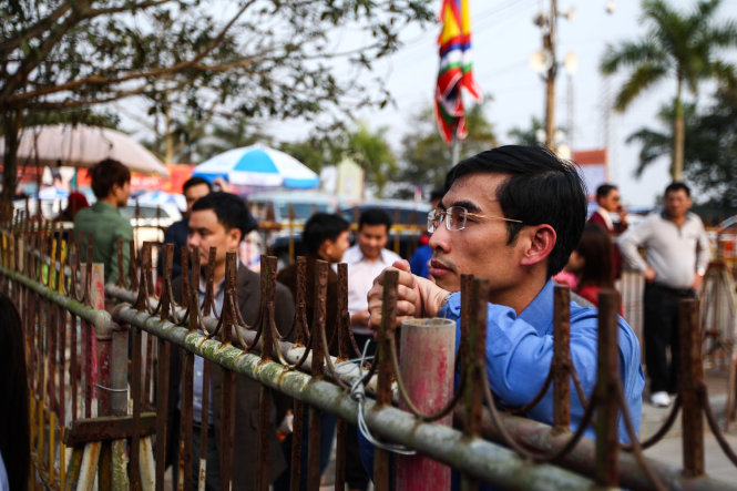 Một người dân đứng cạnh hàng rào sắt phía ngoài cổng đền, để tránh tình trạng quá tải và chèn ép, ban tổ chức đã tổ chức thành nhiều lớp rào an ninh - Ảnh: Nguyễn Khánh