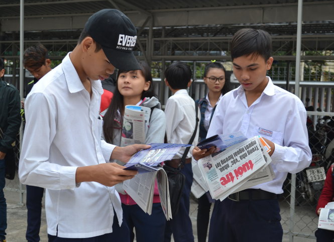 Các học sinh đến sớm tranh thủ đọc báo Tuổi Trẻ - Ảnh: DUY THANH