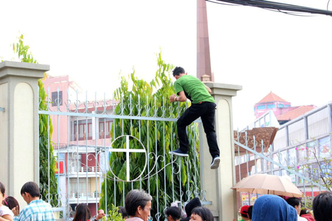Nhiều người dân bất chấp nguy hiểm leo lên hàng rào sắt xem lễ rước kiệu -  Ảnh: Đình Trọng