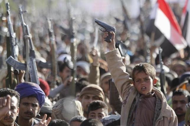 Một cậu bé hô vang khẩu hiệu khi cầm khẩu súng giơ lên trong cuộc tuần hành phản đối Mỹ hỗ trợ chiến dịch không kích của Saudi Arabia tại thủ đô Sanaa của Yemen - Ảnh: Reuters