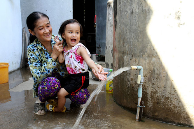 Bà Nguyễn Lệ Thủy và cháu ngoại rất vui mừng khi có nước ngọt sử dụng sau hai tháng trời bị “khát” - Ảnh: V.Trường