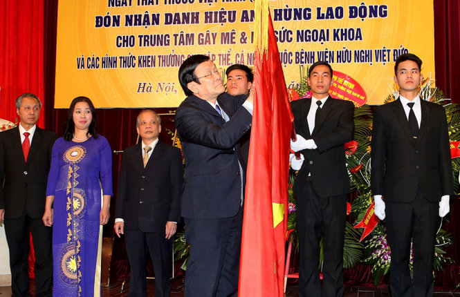 Chủ tịch nước Trương Tấn Sang gắn danh hiệu Anh hùng lao động lên lá cờ truyền thống của Trung tâm gây mê và hồi sức ngoại khoa Bệnh viện hữu nghị Việt Đức - Ảnh: TTXVN