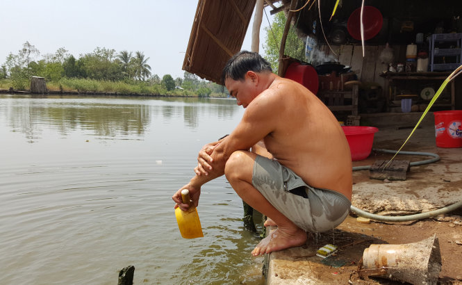 Ông Lữ Văn Thành (xã Đông Thái, huyện An Biên, Kiên Giang) phải tắm bằng nước mặn dưới kênh, sau đó xối lại một ít nước ngọt - Ảnh: Khoa Nam