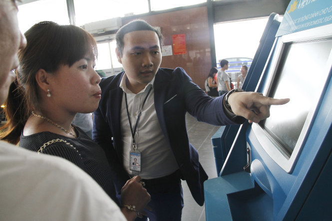 Nhân viên hướng dẫn hành khách làm thủ tục check-in trực tuyến tại các máy làm thủ tục tự động ở sân bay Nội Bài ngày 14-2-2016 ​- Ảnh: Nam Trần