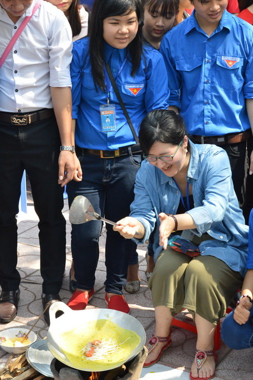 SV ĐH Đồng Tháp hướng dẫn Kumagai Anna (áo xanh ngồi) đổ bánh xèo VN, - Ảnh: Ngọc Tài