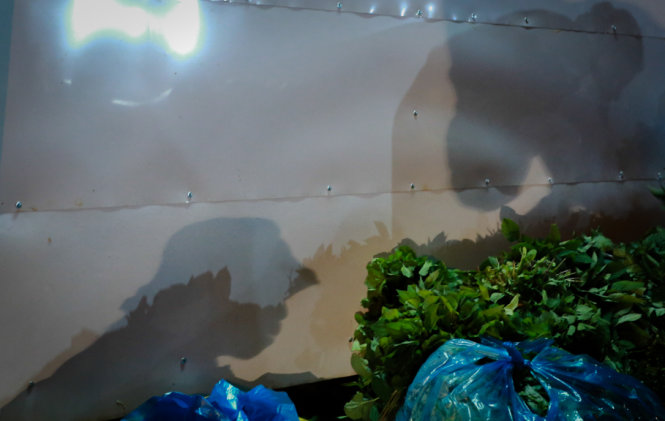 Bóng những người phụ nữ bán rau tại chợ đầu mối  ngả trên bức tường đêm 8-3 - Ảnh: Tiến Thành