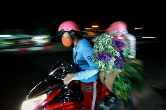 Hai người phụ nữ chở hoa đi bán trong đêm 8-3 tại chợ đầu mối - Ảnh: Tiến Thành