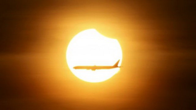 Một chiếc máy bay bay ngang qua mặt trời khi đang diễn ra nhật thực một phần tại Singapore sáng 9-3 - Ảnh: Reuters