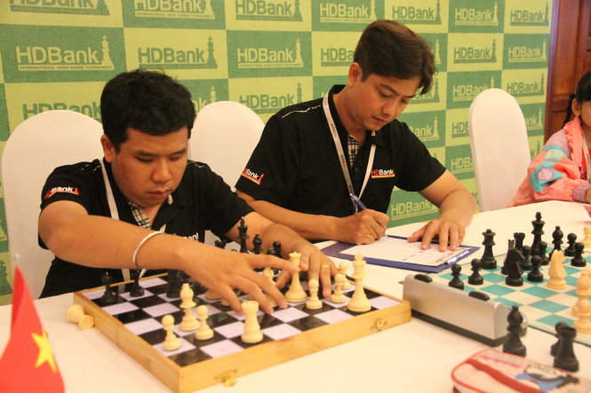 Nguyễn Mạnh Hùng (trái) thi đấu bằng bàn cờ riêng của mình, trong khi trọng tài giúp anh ghi biên bản thi đấu - Ảnh: T.P.