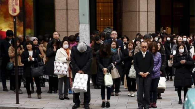 Người đi đường ở Tokyo dừng lại dành 1 phút mặc niệm các nạn nhân động đất-sóng thần - Ảnh: Reuters
