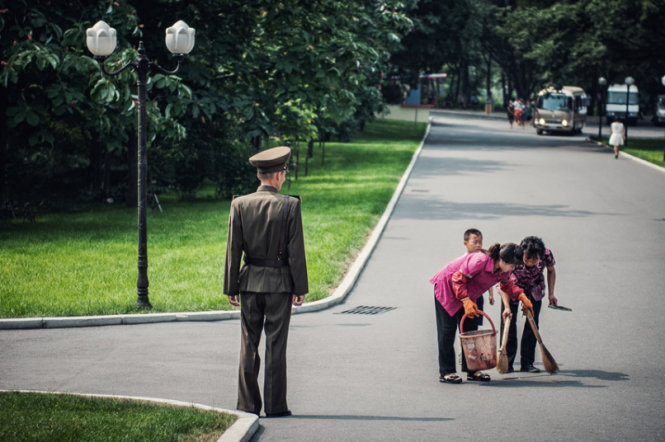 Phụ nữ quét rác trên đường dưới sự theo dõi của một binh sĩ Triều Tiên