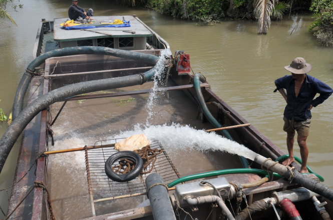 Người trồng sầu riêng ở xã Tam Bình (Cai Lậy) phải vào sâu trong rạch Rau Răm (xã Phú Phong, Châu Thành, Tiền Giang) bơm nước ngọt vào ghe bơm cát để mang về tưới cây - Ảnh: Mậu Trường