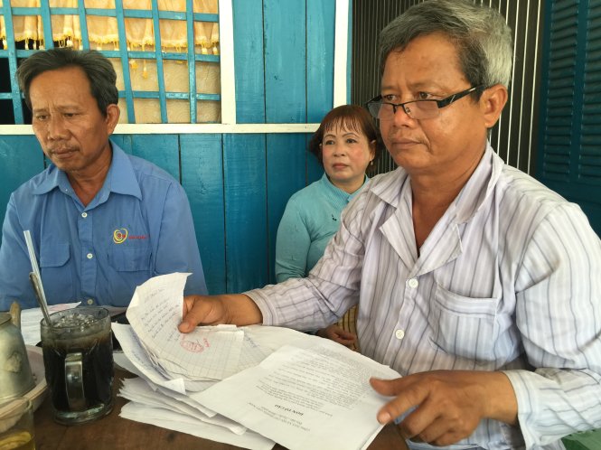 Ông Võ Văn Nhơn (phải) với hợp đồng, giấy hẹn trả nợ của Công ty Năm Nhã trong khi bà giám đốc công ty đã “bặt vô âm tín” - Ảnh: N.Tr.