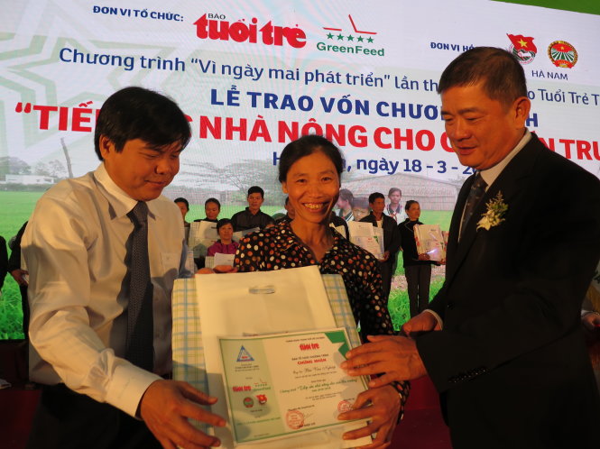 Ông Tăng Hữu Phong - tổng biên tập báo Tuổi Trẻ (trái) và ông Lý Anh Dũng - chủ tịch hội đồng quản trị Công ty cổ phần Greenfeed VN (phải) trao vốn cho nông dân nghèo có con học giỏi - Ảnh: Q.Thế