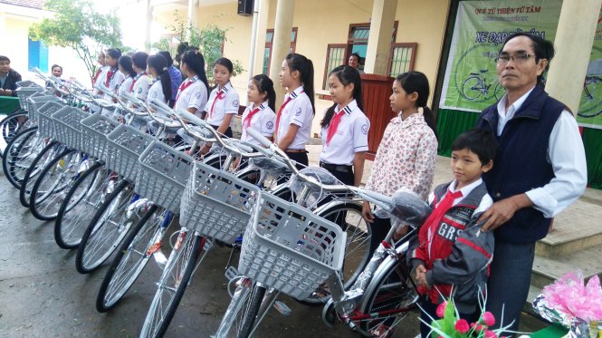 Thầy Nghĩa (bìa phải) trao quà là những chiếc xe đạp mới cho học trò nghèo - Ảnh: Trần Mai
