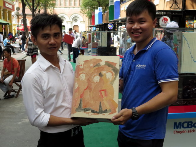 Nhân viên MCBooks bê quyển từ điển có bìa giấy dó là bức tranh của họa sĩ Phan Cẩm Thượng chuẩn bị trưng bày tại đường sách - Ảnh: Lam Điền