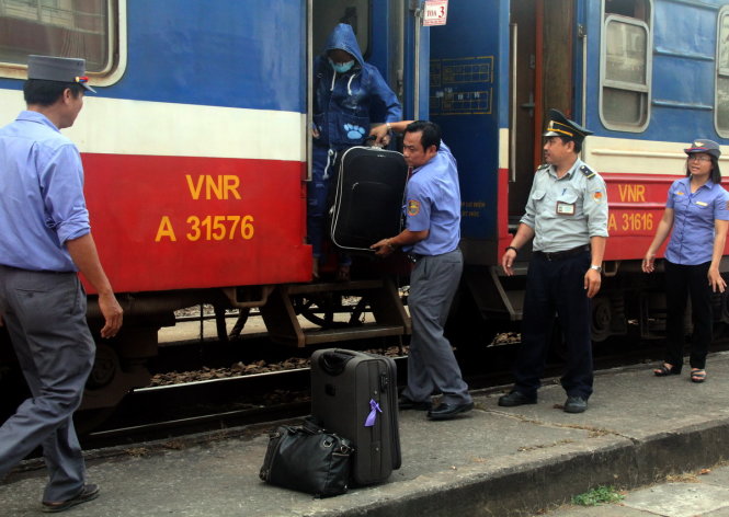 Nhân viên đoàn tàu phụ giúp hành khách đưa hành lý xuống ga Sóng Thần để lên ô tô về ga Biên Hòa