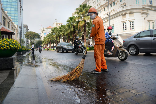 Công nhân làm vệ sinh vỉa hè và lòng đường Lê Thánh Tôn, quận 1, TP.HCM được lát bằng đá granit - Ảnh: Hữu Khoa