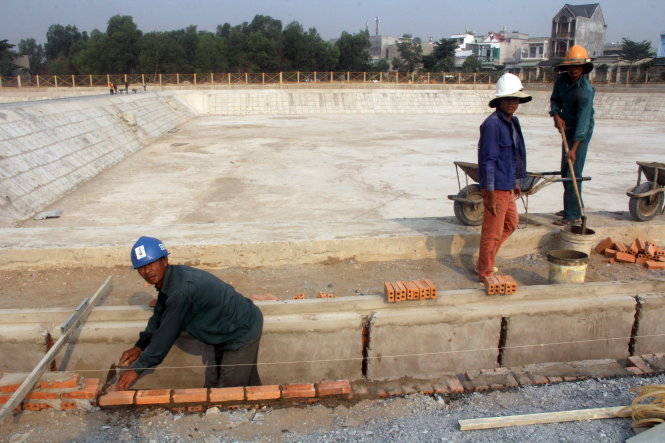 Công nhân hoàn thiện hạng mục hồ sinh học thuộc dự án cải tạo kênh Ba Bò sáng 29-3 - Ảnh: Quang Khải