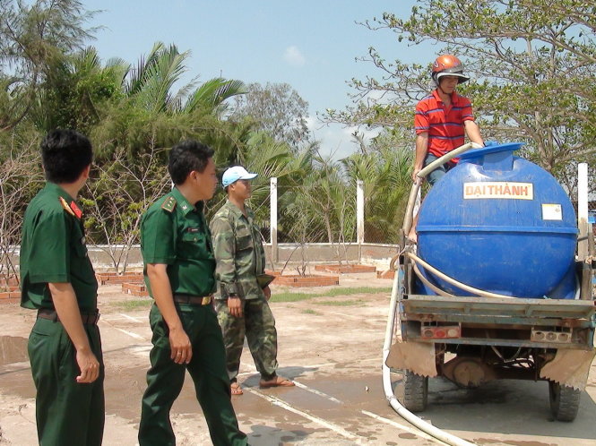 Một người dân dùng xe máy cày đến để nhận nước từ tàu vận tải quân sự.