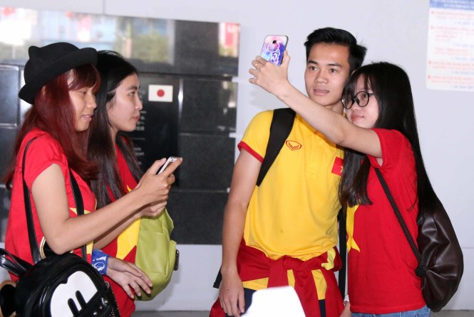Tiền đạo Văn Toàn chụp hình cùng các CĐV tại sân bay Tân Sơn Nhất. Ảnh: N.K