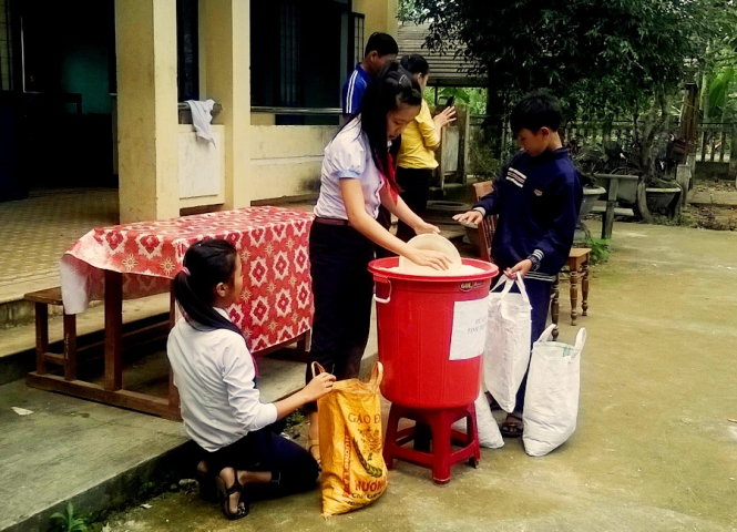 Các em học sinh góp gạo để chia sẻ khó khăn của bạn bè - Ảnh: T.P.