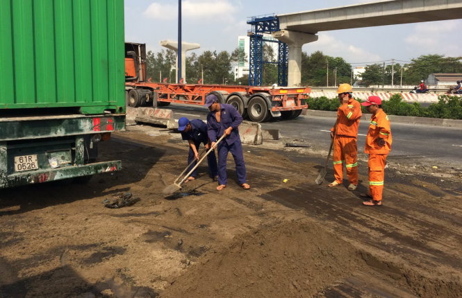 Các nhân viên công ích đang đổ cát xử lý nhớt tràn ra đường - Ảnh: Lê Phan