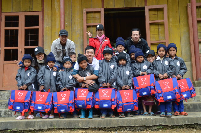 Nguyễn Bình Nam (áo thun trắng, ôm một em nhỏ) cùng các thành viên trong nhóm tặng quà là cặp sách và áo ấm mới cho học sinh nghèo vùng cao Nam Trà My, Quảng Nam - Ảnh: Hồng Nguyên