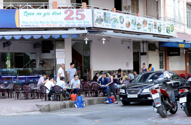 Quán ăn trên đường Hoàng Sa (TP.HCM) bày bàn ghế chiếm trọn lề đường và dùng lòng đường làm bãi giữ xe - Ảnh: Duyên Phan