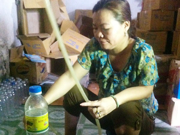 Bà Kim thực hiện lại việc pha dấm ăn bằng acid và nước lã - Ảnh: Công an cung cấp
