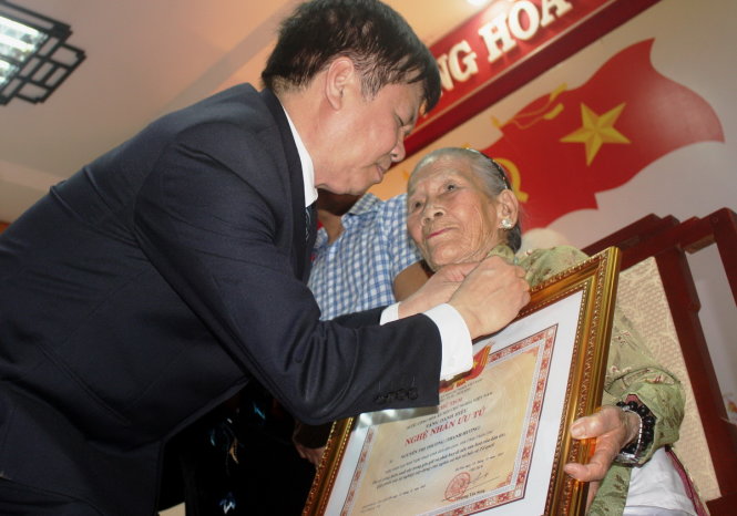 Ông Nguyễn Dung, phó Chủ tịch UBND tỉnh Thừa Thiên-Huế, gắn huy hiệu và trao quyết định cho nghệ nhân Thanh Thương - Ảnh: NHẬT LINH