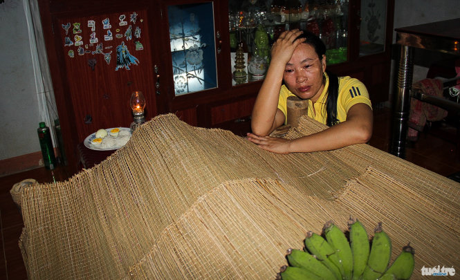 Chị Cô Thị Minh Hồng ngồi thẫn thờ bên thi thể của em Võ Thành Chung trong khi chờ chồng đi làm xa về - Ảnh: Trần Mai