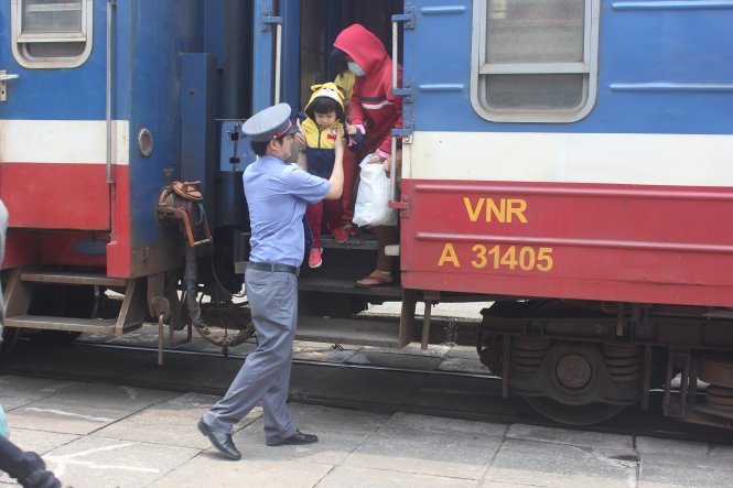 Nhân viên ngành đường sắt giúp nữ hành khách bế em bé xuống tàu - Ảnh Đức Phú