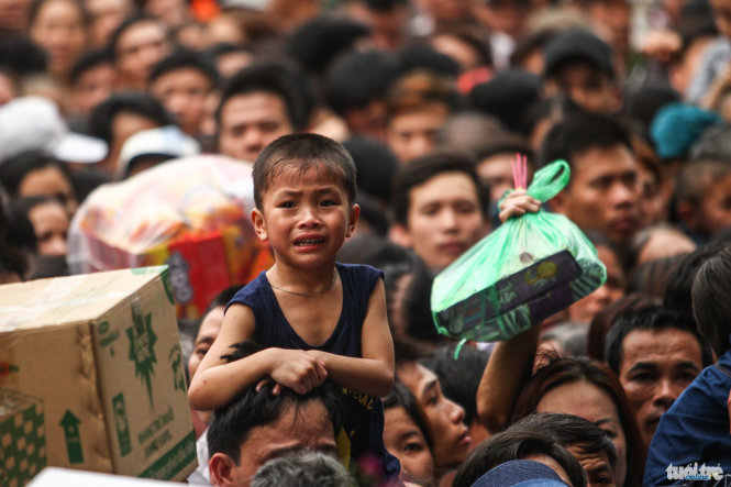 Do lượng người quá lớn cộng với cổng đền quá nhỏ nên việc di chuyển của người dân gặp nhiều khó khăn, trong ảnh một bé trai bật khóc mặc dù được bố cõng trên vai - Ảnh: Nguyễn Khánh