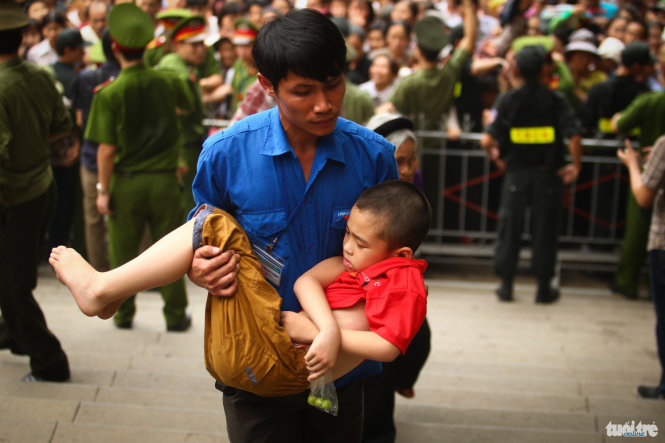 Môt cậu bé nhanh chóng được một nhân viên của ban quản lý Đền Hùng đưa vào khu vực an toàn để tránh đám đông - Ảnh: Nguyễn Khánh