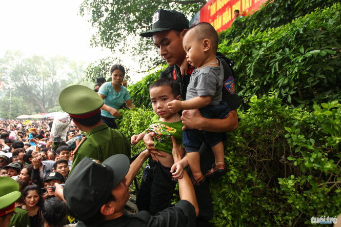 Một chiến sĩ cảnh sát cơ động ôm hai trẻ nhỏ tách khỏi đám đông - Ảnh: Nguyễn Khánh