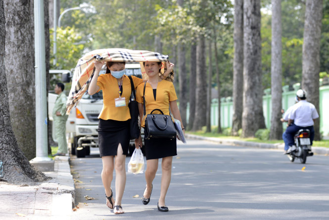 Hai cô gái Sài Gòn che chung một chiếc khăn dưới cái nắng hầm hập bất thường - Ảnh: Duyên Phan